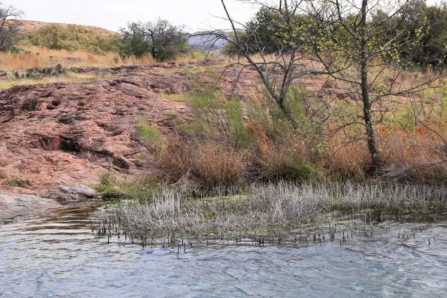 Pink granite gneiss outcrop dropping straight into the water at Inks Lake State Park, Burnet County.
